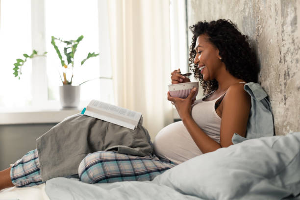 Smiling pregnant woman having breakfast in bed.