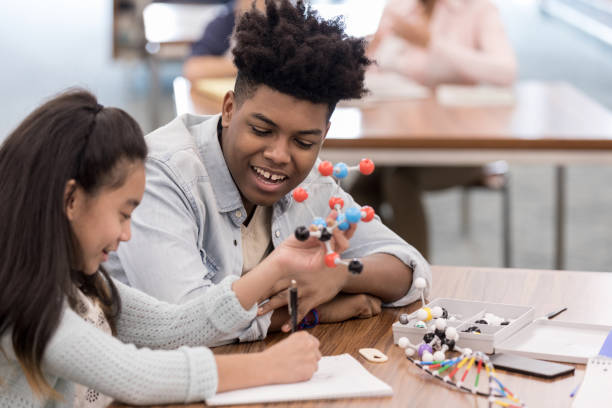 istock Girl draws molecule while teen helps 1155064216