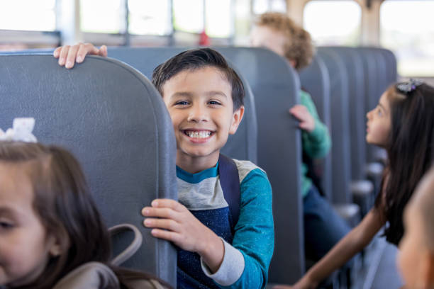 colegial sonríe excitadamente mientras está sentado en el autobús escolar - autobús fotos fotografías e imágenes de stock