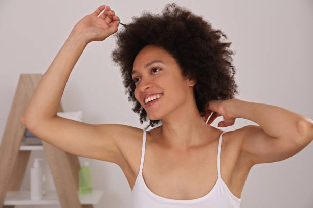 Armpit epilation, laser hair removal. Young woman holding her arms up and showing underarms, smooth clean skin stock photo