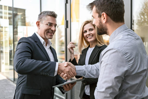 istock Business people shaking hands in front of office 1155067940