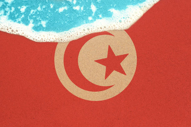 istock Sea wave on the sunny sandy beach with flag Tunisia. View from top on surf. 1155069680
