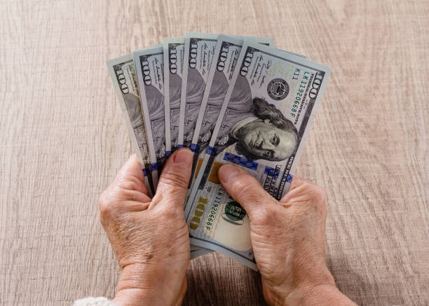 istock Cropped Hands Holding Us Currency On Table 1155069919