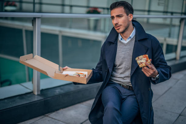 istock Man eating pizza outdoors 1155071383