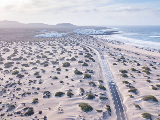 Lanzarote coast, aerial landscape of car driving in Canary islands beautiful road in sand desert in Lanzarote coast, aerial landscape of car driving in Canary islands caleta de famara lanzarote stock pictures, royalty-free photos & images