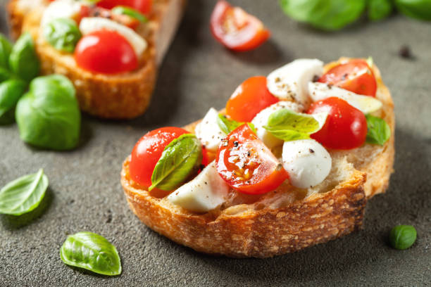 bruschetta aux tomates, fromage mozzarella et basilic sur une ancienne table rustique. apéritif ou collation italien traditionnel, antipasto - bruschetta tomato bread mozzarella photos et images de collection