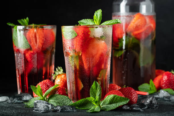istock Fresh lemonade with ice, mint and strawberry on top in glass on black table background. Cold summer drink. Sparkling glasses with berry cocktail 1155076064