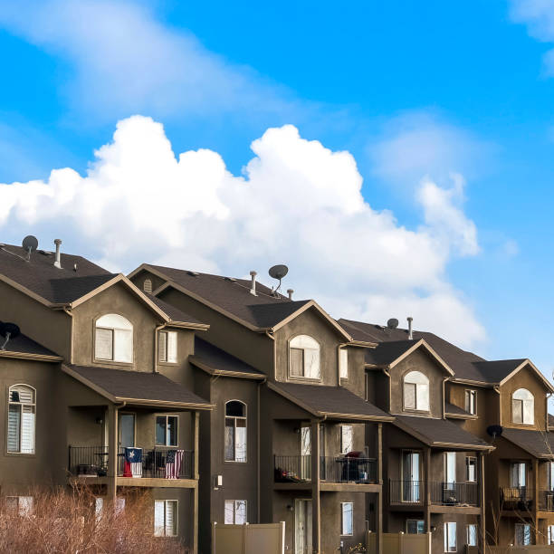istock Square Houses with balconies and arched windows against blue sky with puffy clouds 1155076656