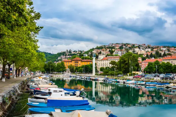 Rijeka, Croatia: View from Rjecina river over the city of Rijeka with Liberation Monument and boats in front and colorful buildings and Trsat castle on the hill in the background