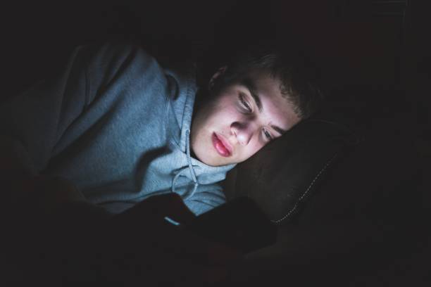 Teenager on his smartphone in the dark. stock photo