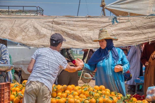 Oued Laou, Tetouan, Morocco - May 4, 2019: A woman buying oranges in the souk of Oued Laou, a village in the province of Tetouan