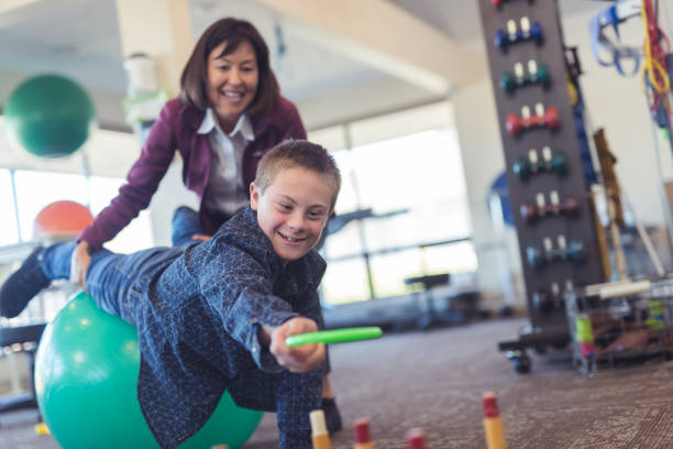 ein junge macht workouts mit einem ergotherapeuten in einer physiotherapie-klinik - physical and occupational therapists stock-fotos und bilder