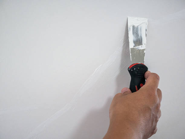 istock Plasterer hand repair crack white wall 1155091661
