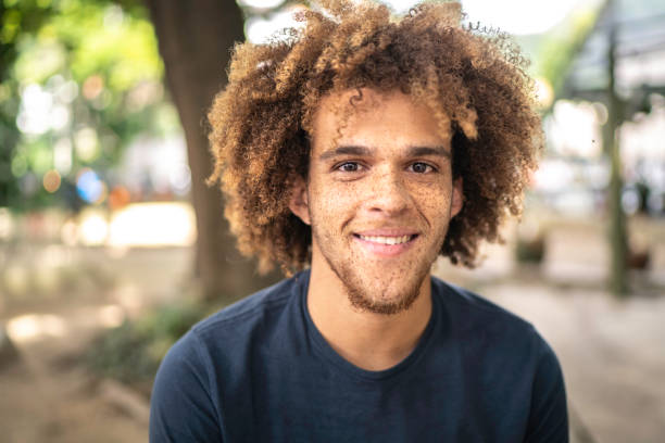 verticale de jeune homme de sourire sur la rue - tache de rousseur photos et images de collection