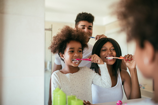 Photo of happy afro-american family washing their teeth during daily morning routine.
