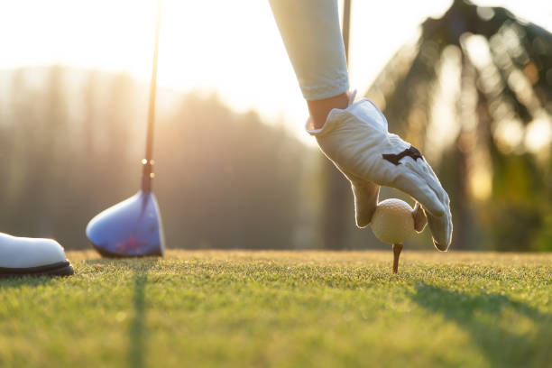 ręka kobiety golfista delikatnie umieścić piłkę golfową na drewnianą koszulkę na tee off, aby gotowy hit od tee off do toru wodnego przed. koncepcja zdrowego i stylu życia. - golf zdjęcia i obrazy z banku zdjęć