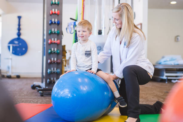istock Young boy working with a physical therapist at a clinic 1155105470