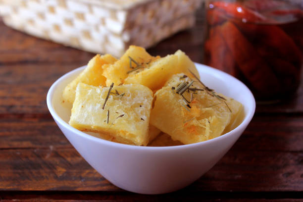 boiled and fried cassava (mandioca) in ceramic bowl on rustic wooden table in restaurant
