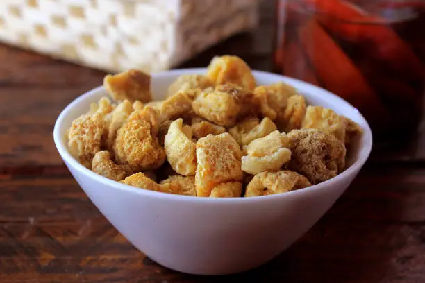 Photo of pork rinds (torresmo) fried in ceramic bowl on rustic wooden table in restaurant. typical dish of Brazilian and Asian cuisine