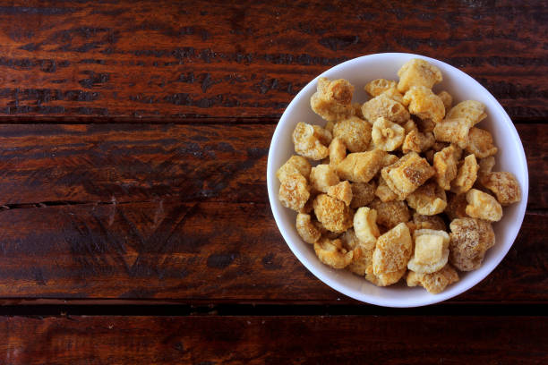 istock pork rinds (torresmo) fried in ceramic bowl on rustic wooden table in restaurant. typical dish of Brazilian and Asian cuisine 1155106259