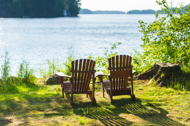 istock Muskoka chairs facing a lake with blue water 1155107645