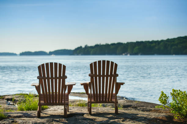 istock Two Adirondack chairs facing a lake at sunset 1155107904