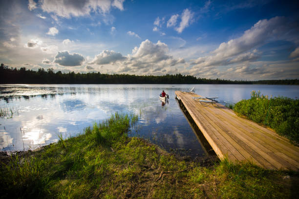 istock Sunset on a lake with a canoe leaving the pier. 1155107970