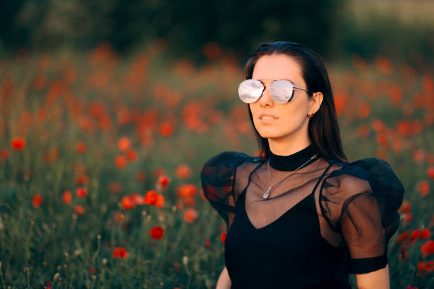 coole frau mit trendiger sonnenbrille in einem feld von mohnblumen - puffed sleeve stock-fotos und bilder