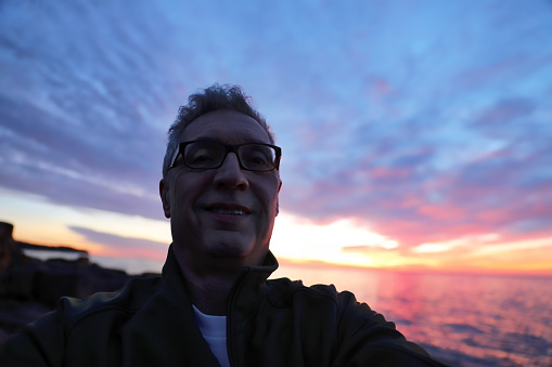Self Portrait of senior man enjoying sunrise on Lake Superior in Minnesota