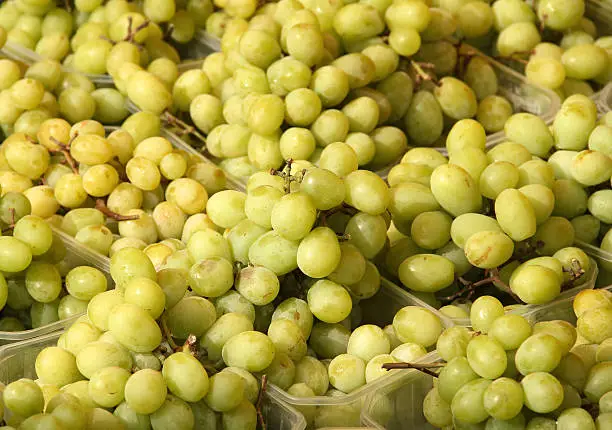 Fresh yellow grapes in baskets at market