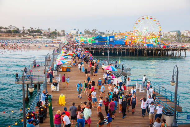 переполненный пирс санта-моники с туристами и местными жителями - amusement park santa monica ferris wheel santa monica beach стоковые фото и изображения