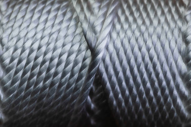 a macro of a spool of string wound in a very symmetrical pattern on a tube.  the image is in very sharp focus and has a high contrast.    the symmetry in the pattern is very geometrical and the winding is done in a very ocd fashion. - nylon strings imagens e fotografias de stock