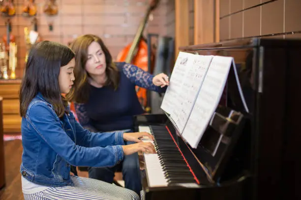 Piano teacher is instructiong her student.