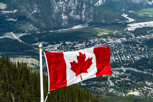 Canadian Maple Leafe Flag flying over mountains in national park