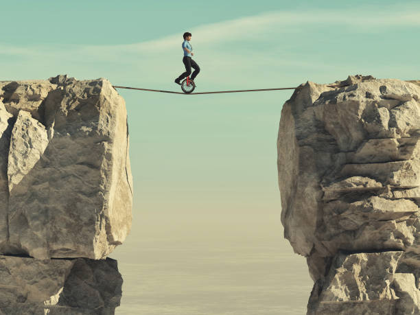 istock Man ride a mono cycle and balancing a slackline between two mountain peaks. This is a 3d render illustration 1155127500
