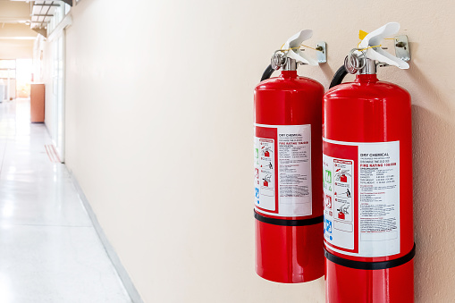 Close-up View Of Fire Extinguisher Cabinet On Wall With Blurred Kitchen Background