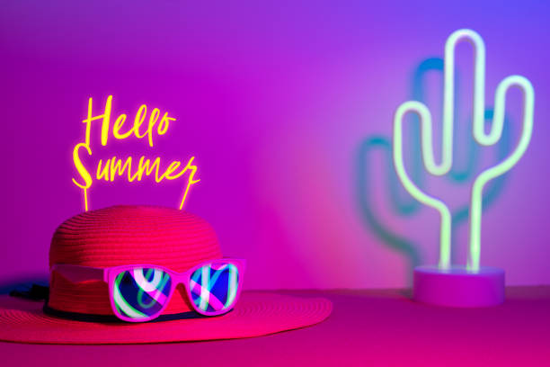 istock Hello Summer with hat and sunglasses refection neon light with cactus on  pink and blue light on table with copy space.Trendy vacation holiday background. 1155129899