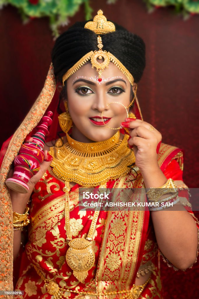 Un modèle féminin assez jeune portant la tenue nuptiale indienne/bangladeshi traditionnelle avec des bijoux et le maquillage lourds d’or - Photo de Adulte libre de droits