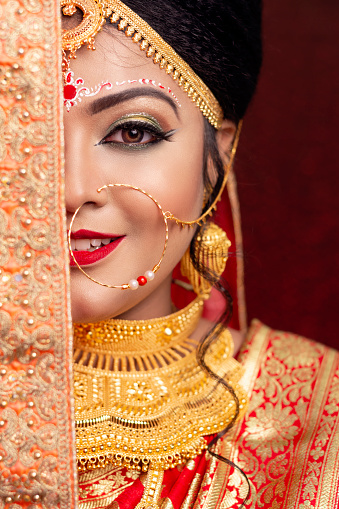 A pretty young female model wearing traditional indian / Bangladeshi bridal outfit with heavy jewelry and makeup