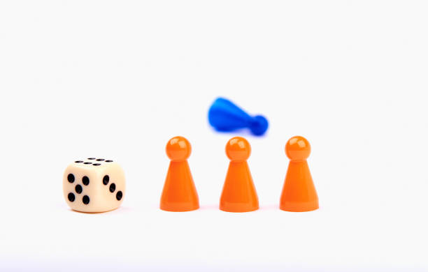 istock Three orange game pieces with a dice and a blue figure lying behind them. Isolated on white background. 1155136388