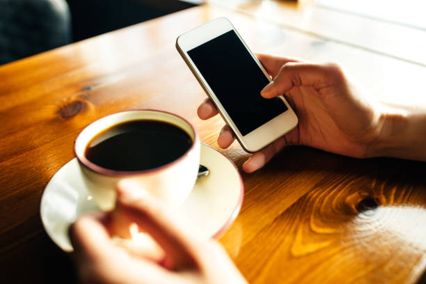 Woman using smartphone on wooden table in cafe. Close-up image with social networks concept