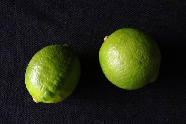 istock Two green limes against black background 1155138638