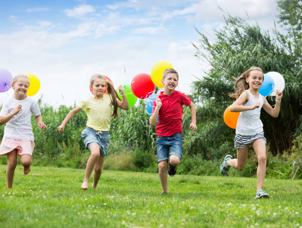 istock Four positive kids running on green lawn 1155138743