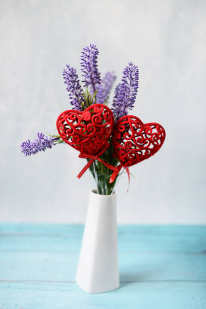 Beautiful summer bouquet with  lavender in a white vase with hearts decoration on a wooden background for a birthday and Valentine's Day\