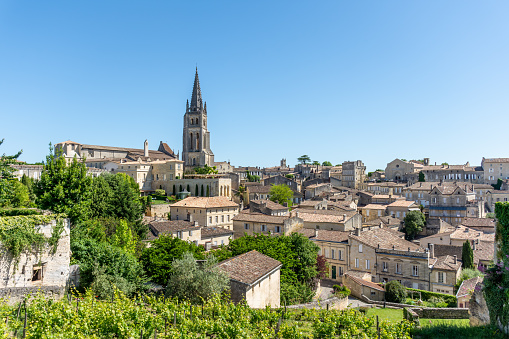 Street with historic buildings and a stream on the outskirts of Falaise. Saint-Laurent church on a hill in the background