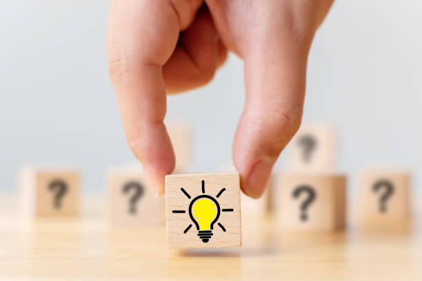 istock Concept creative idea and innovation. Hand picked wooden cube block with question mark symbol and light bulb icon 1155140890