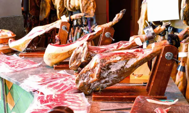 Photo of Legs of traditional Spanish jamon fixed on wooden jamoneras ready for sale