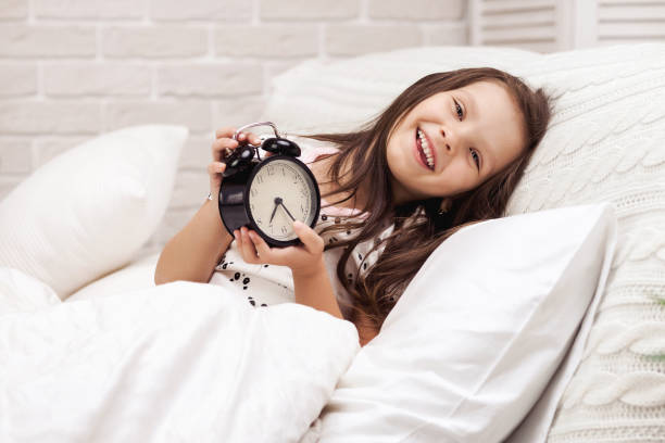 istock little child girl in pyjamas with clock 1155143430