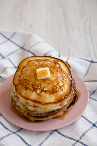 istock Homemade pancakes with butter and maple syrup on a pink plate, low angle view. Copy space. 1155143789