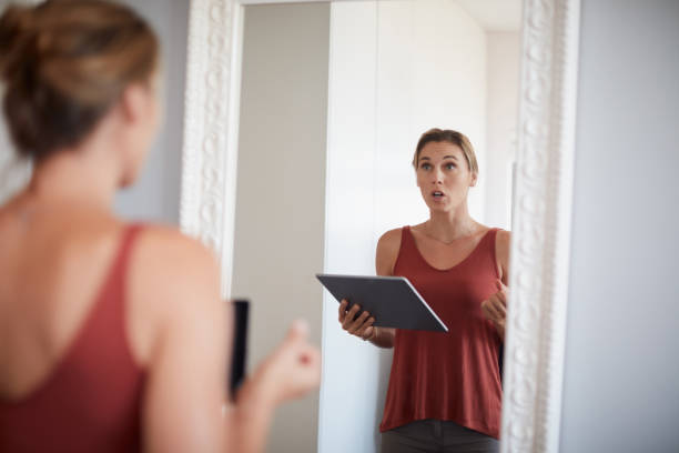 Practice makes perfect Cropped shot of an attractive young woman having a rehearsal in the mirror while holding a digital tablet practicing stock pictures, royalty-free photos & images